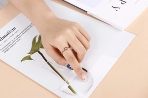 Close-up of minimalist rose gold ring with a single zircon on a woman's finger
