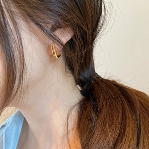 Close-up of a model wearing a minimalist gold geometric C-shaped earring with metallic finish