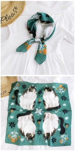 Detail of green silk-like square scarf featuring cat patterns and orange lily floral prints