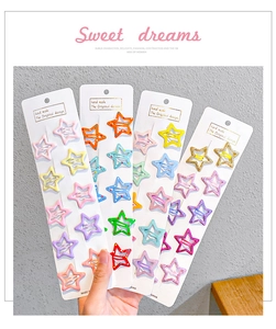 Close-up of star-shaped candy-colored metal hair clips on display cards in multiple colors