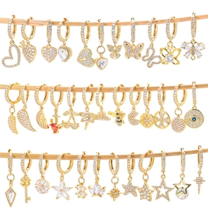Collection of gold-plated earrings with colorful zircon inlays displayed on a wooden stand