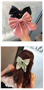 Close-up of large layered satin bow hair clips in black, pink, and mint green colors