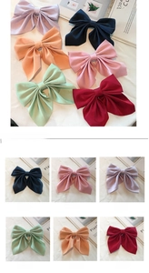 Detailed view of large satin bow hair clips in six colors including navy and wine red