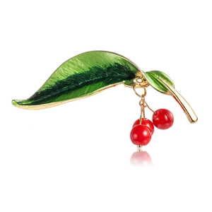 Elegant gold cherry brooch with green enamel leaves and red beads on white background