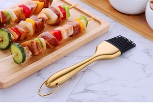 Dettaglio pennello da cucina in silicone con manico dorato su piano in marmo