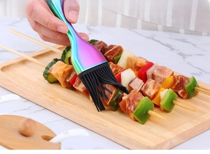 Dettaglio pennello da cucina in silicone con manico arcobaleno su spiedini di carne