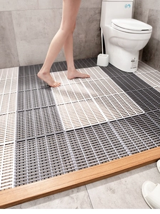 Close-up of grey and white TPE anti-slip bath mats with feet showing drainage holes