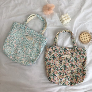 Flat lay of vintage floral cotton handbags with a white fabric and aesthetic props
