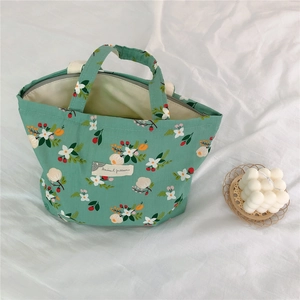 Detail of green floral cotton handbag with white flowers and red fruit patterns