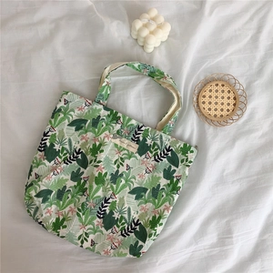 Close-up of a small floral cotton tote bag with green cactus pattern on white bedding