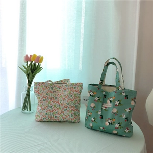Close-up of floral cotton tote bags in red and green patterns on a plaid tablecloth