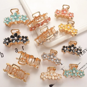 Detail view of colorful floral alloy hair claws with elegant pearl centers and gold finish