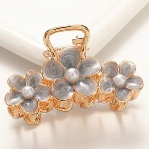 Detailed close-up of golden alloy hair claw with marble texture flowers and pearls