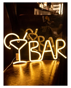 Close-up of yellow cocktail glass and BAR text LED neon sign on a dark leather chair