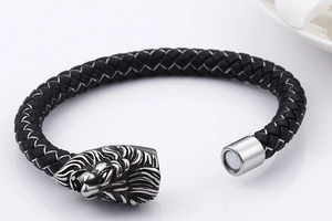Macro detail of black braided leather bracelet with silver lion head and magnetic clasp