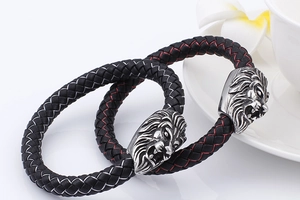 Close-up of silver lion head charms on black braided leather bracelets for men