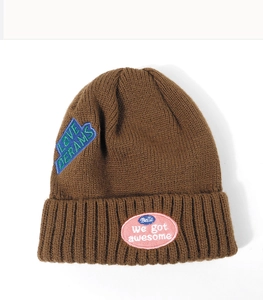 Detail of dark brown ribbed knit beanie featuring pink and blue embroidered patches