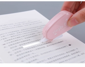 Pink Morandi correction tape used by hand on white paper with a blurred background
