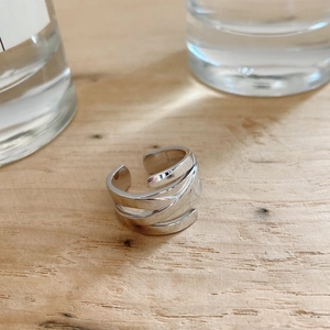 Close-up of woven multilayer S925 sterling silver ring on a minimalist wooden surface