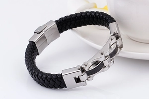 Detail of men's braided leather bracelet with stainless steel clasp on a white surface