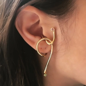 Minimalist gold ear cuff featuring twisted metal lines and two small colored gemstones