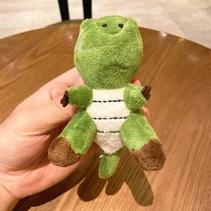 Cute green plush crocodile keychain doll with white belly on a warm wooden background