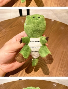 Close-up of a green plush crocodile keychain with white belly stripes and hand grip detail