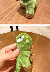 Close-up of green plush dinosaur keychain with soft fur and detailed brown claws