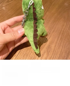 Detailed back view of green plush dinosaur keychain with soft brown scales and metal clip