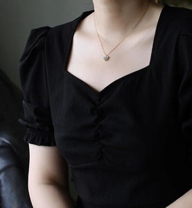 Close-up of heart-shaped green pendant necklace with golden bead chain on model