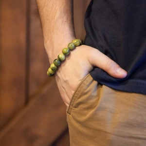 Close-up of 10mm natural yellow-green gemstone beaded bracelet worn on a male wrist