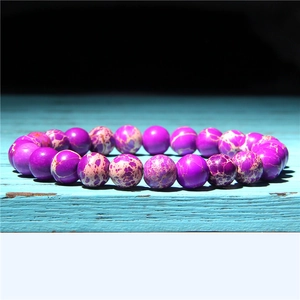 Macro detail of natural purple sunstone beads with unique marble texture on a wood surface