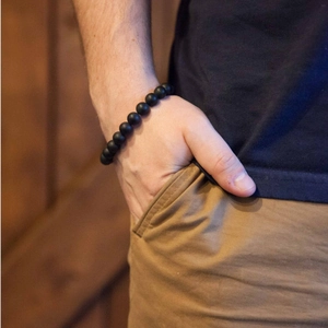 Close-up of matte black natural stone beaded bracelet worn by a male model