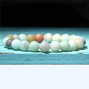 Macro shot of 8mm-10mm natural sunstone and amazonite beaded bracelet on blue wood