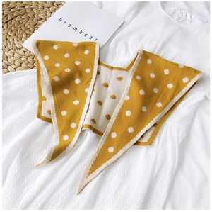 Close-up of yellow knit shawl with white polka dots on a white dress texture