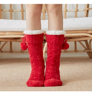 Detailed view of red knitted thermal socks with white faux fur trim and cute pom-poms