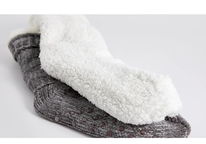 Detailed view of plush white lining and grey knit fabric with non-slip dots on sole