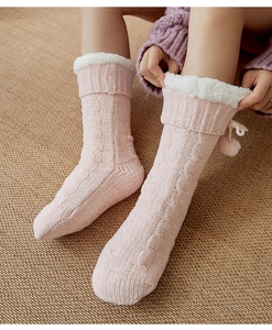 Detail of pink knitted floor socks with white faux fur trim and decorative pom-poms