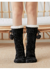 Close-up of black chenille floor socks with white fleece trim and cute pom-pom details