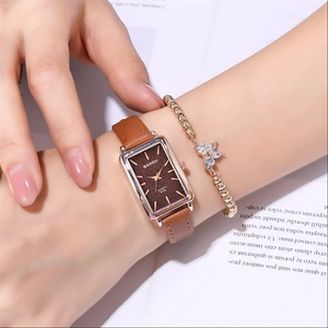 Close-up of rectangular rose gold watch with brown leather strap and floral bracelet