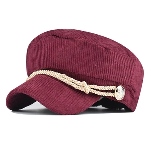 Macro shot of burgundy corduroy newsboy cap showing texture and lion gold button