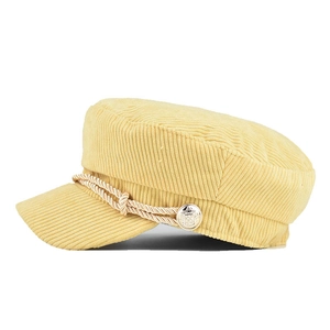 Detail of yellow corduroy newsboy cap with white braided rope and silver crest button
