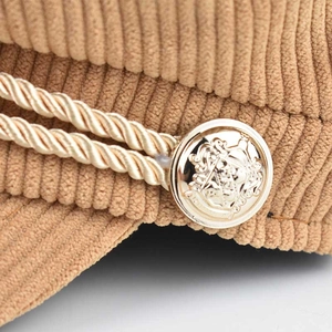 Detailed close-up of corduroy texture with vintage gold emblem and braided rope trim