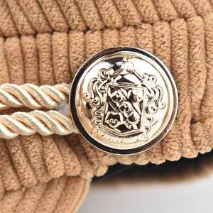 Detailed close-up of khaki corduroy fabric with golden braided rope and vintage metal button
