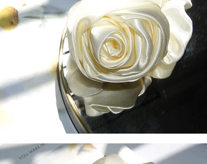 Close-up of champagne satin rose hair scrunchie with silky texture on mirror surface