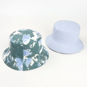 Flat lay of tie-dye and light blue reversible cotton bucket hats for sun protection