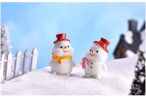 Close-up of two cute resin snowman figurines in a snowy miniature landscape setting
