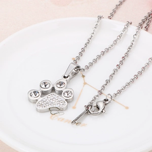 Sparkling silver paw pendant necklace with inlaid crystals on white ceramic background