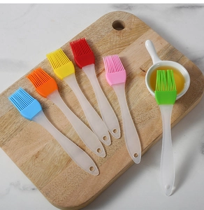 Set of six colorful silicone BBQ brushes with clear handles on a wooden cutting board