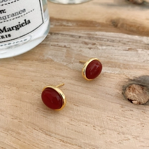 Close-up of vintage oval red agate stud earrings with gold plating on wooden surface